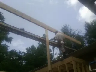 Carpenter setting a ridge beam over a new addition frame — Ice Dam Removal by Roofing Brothers in Liscomb
