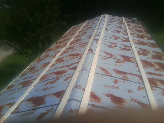 Rusted metal roof panels with new wood purlins before replacement — Storm Damage Roof Repair in Liscomb by Roofing Brothers