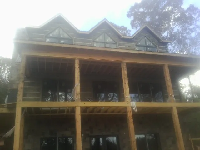 Dormers and porch framing on a large log home under construction — Roof Coating work by our crew in Liscomb
