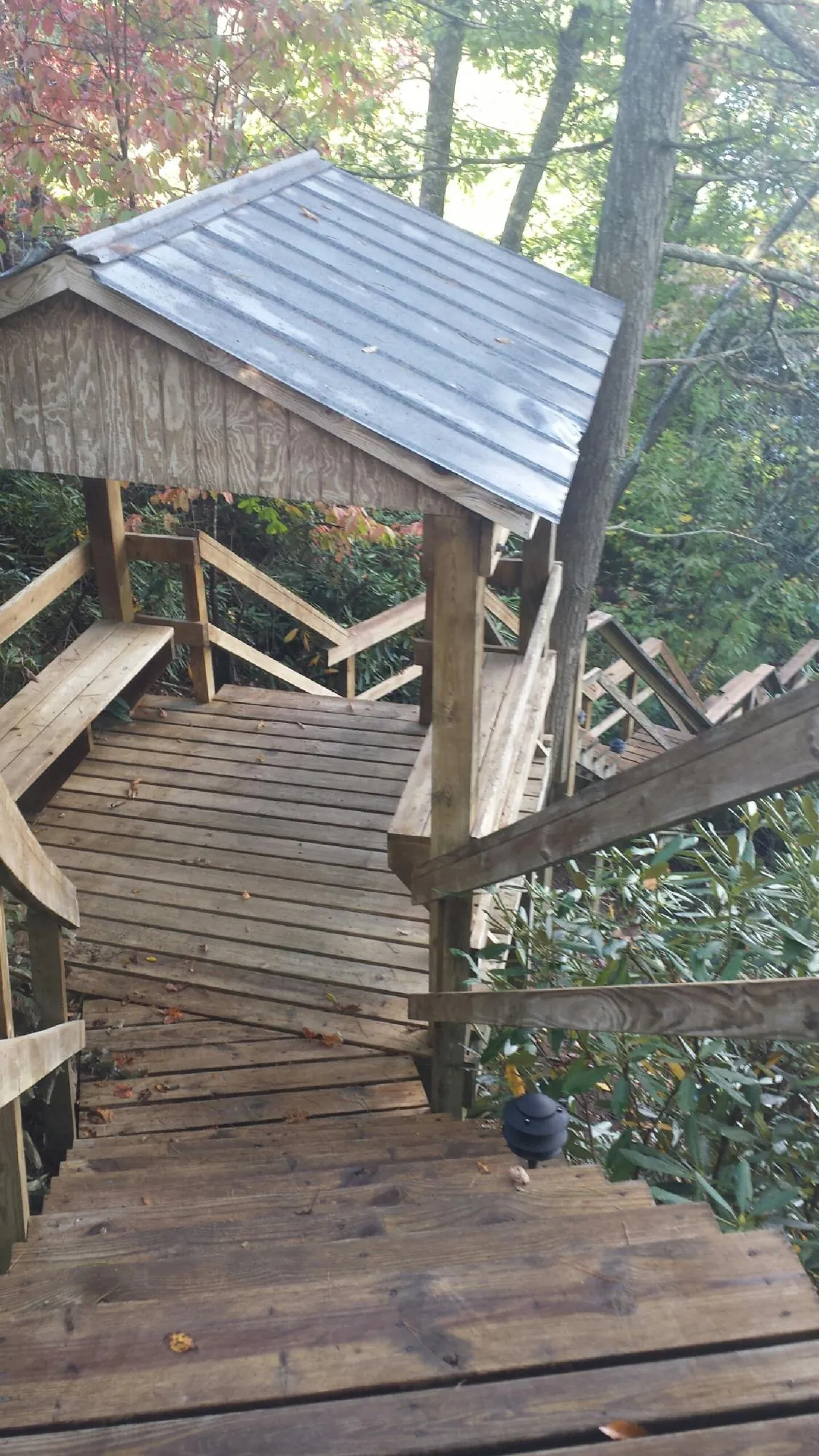 Metal roofed shelter over wooden steps on a wooded walkway — Skylight Repair & Installation work by our crew in Liscomb