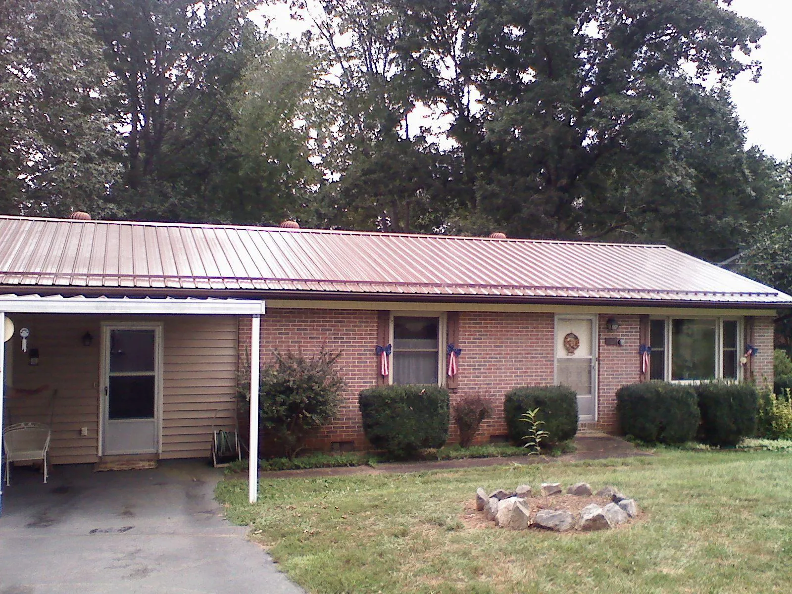 Bronze metal roof and carport on a brick ranch home — Roof Repair work by our crew in Liscomb