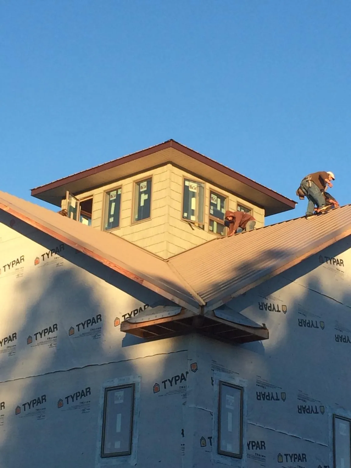 Roofers working around a rooftop cupola on a new metal roof at sunset — Roof Waterproofing in Liscomb by Roofing Brothers